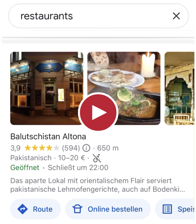 Screenshot aus dem verlinkten Video, im Video ist zu sehen, dass das servierte Essen dampft und jemand sich im Hintergrund etwas Brot von einem Teller nimmt.